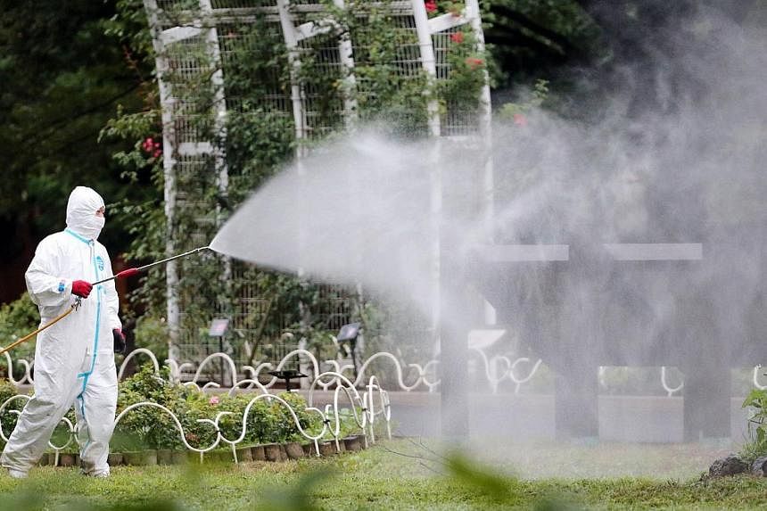 This picture taken on Aug 28, 2014, shows a worker spraying insecticide at the Yoyogi park, one of the largest open spaces in central Tokyo, believed to be the source of the mosquito-borne dengue fever. -- PHOTO: AFP