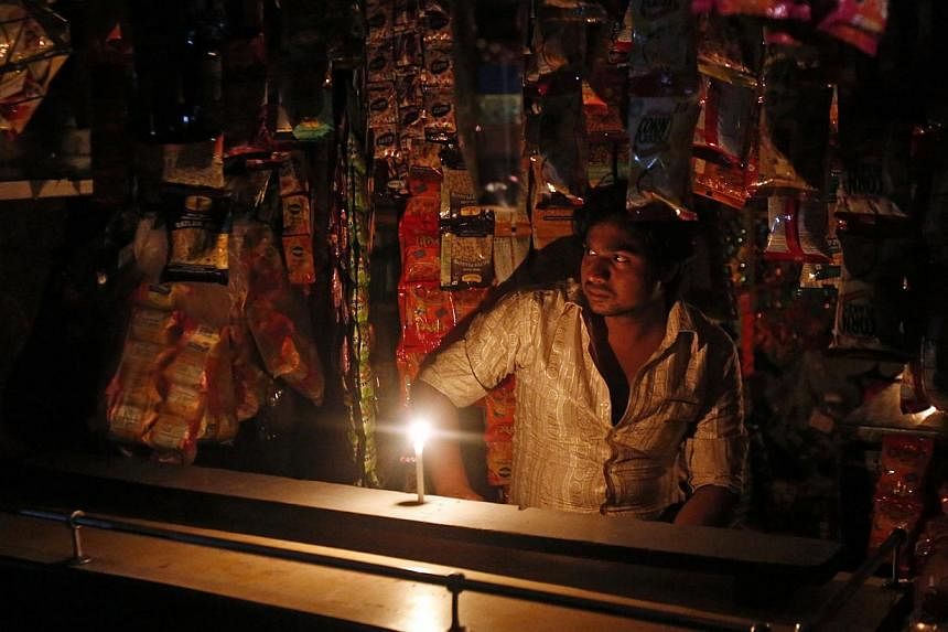 A shopkeeper waits for customers at a grocery shop during a power-cut in Mumbai on Sept 2, 2014. -- PHOTO: REUTERS
