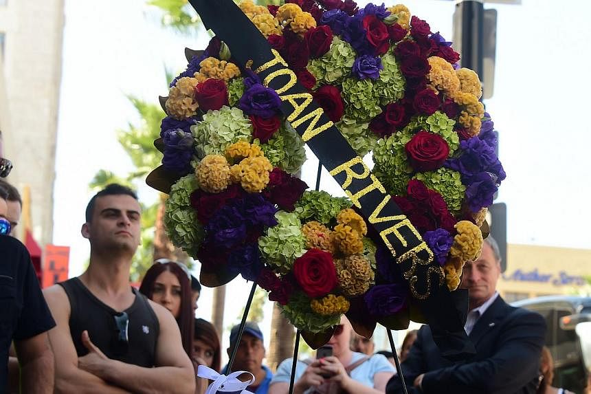 Onlookers gather beside a wreath of flowers placed on the Hollywood Walk of Fame Star for Joan Rivers in Hollywood, California on Sept 4, 2014, following news of the comedian's death in New York at the age of 81. -- PHOTO: AFP