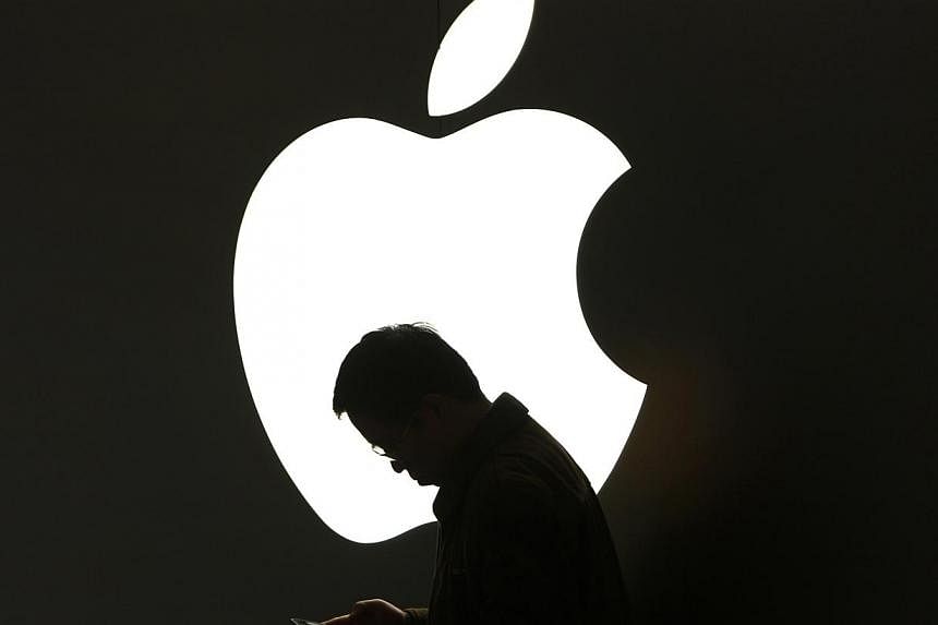 A man looks at his Apple iPad in front an Apple logo outside an Apple store in downtown Shanghai in this file photo. &nbsp;A new investigative report has said that a chinese factory that supplies Apple with parts has been violating &nbsp;basic standa
