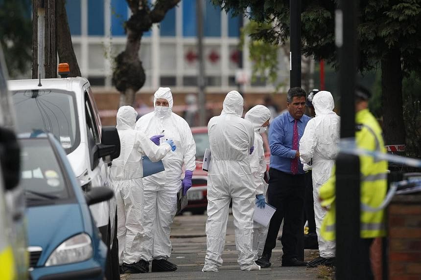 Police forensics personnel are pictured on a street in Edmonton, north London on Sept 4, 2014, after a woman was found dead following a suspected beheading in a residential garden. -- PHOTO: AFP