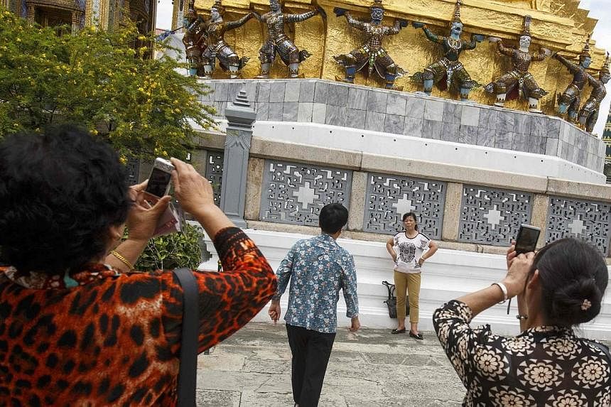 Chinese tourists take photographs as they visit the Grand Palace in Bangkok on Sept 4, 2014.&nbsp;To make vacationing in a country still under martial law a little more attractive, Thailand's military junta is offering tourists from China free visas.