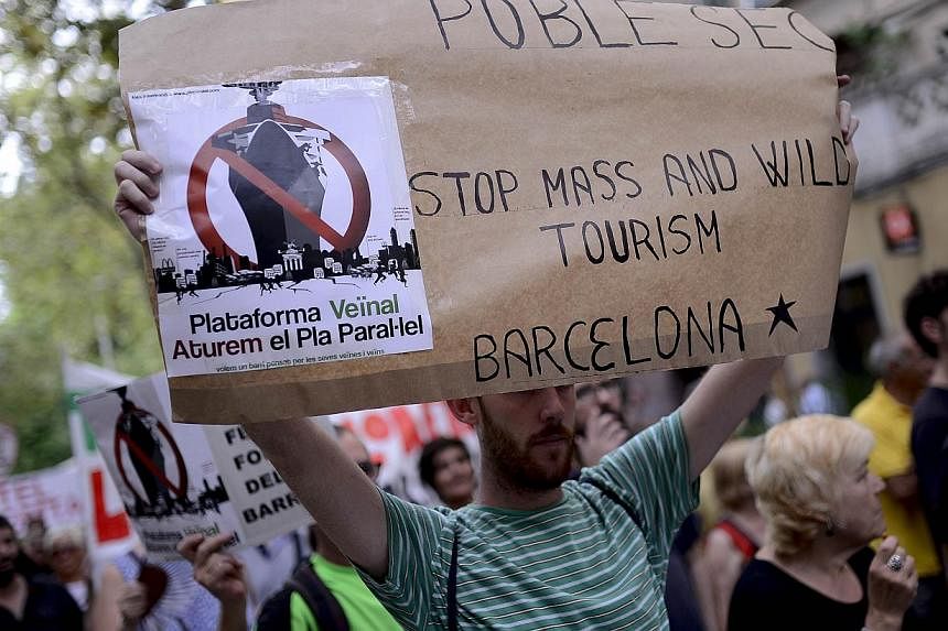 A picture taken on Aug 30, 2014 shows a resident of La Barceloneta holding a placard during a demonstration against "drunken tourism" in their neighbourhood in Barcelona. -- PHOTO: AFP