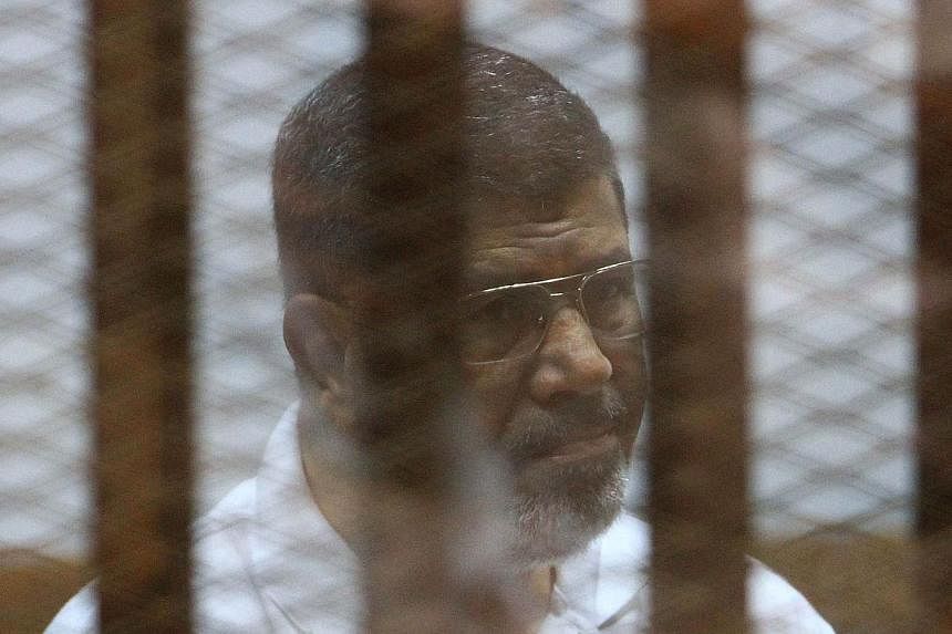 Egypt's deposed Islamist president Mohamed Mursi, charged along with 130 others of plotting attacks and escaping from prison in 2011, sits inside the defendant’s cage during his trial at the police academy in Cairo on Aug 18, 2014.&nbsp;An Egyptian