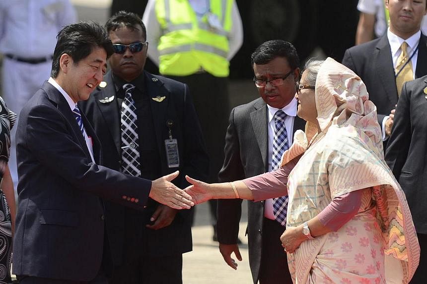 Japanese Prime Minister Shinzo Abe shaking hands with Bangladeshi Prime Minister Sheikh Hasina following his arrival at the Hazrat Shahjalal International Airport in Dhaka on Sept 6, 2014. Mr Abe arrived in Dhaka for a three-day visit to Bangladesh a