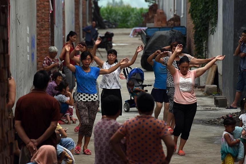 A group of women take part in an early morning dance session, as villagers look on, in Weijian village, in China's Henan province on July 30, 2014.&nbsp;Some have labelled the dancing women ridiculous and annoying, while others believe that they dese
