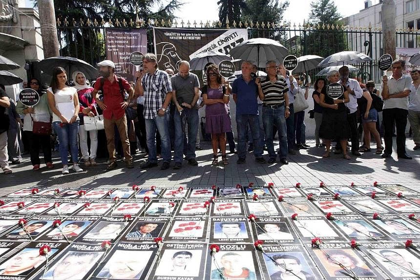 Demonstrators stand behind pictures of victims who died in previous work accidents, in protest of Saturday's accident which killed ten workers at a construction site, in central Istanbul Sept 7, 2014. -- PHOTO: REUTERS