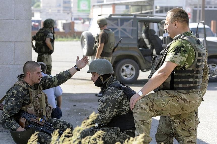 Ukrainian servicemen stand guard on Sept 7, 2014 at a Ukrainian army checkpoint on the outskirts of the key southeastern port city of Mariupol, after an overnight bombing attack. -- PHOTO: AFP
