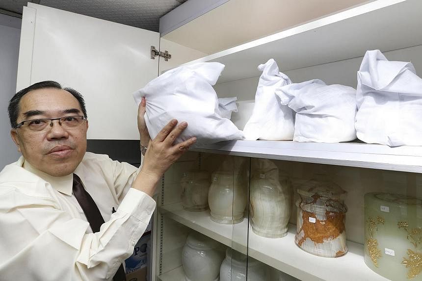 Trinity Casket operations manager Dave Lim with the uncollected bags of ashes, kept in a cabinet in his office in Sin Ming Drive. The oldest bag dates back to 1997. -- ST PHOTO: CHEW SENG KIM