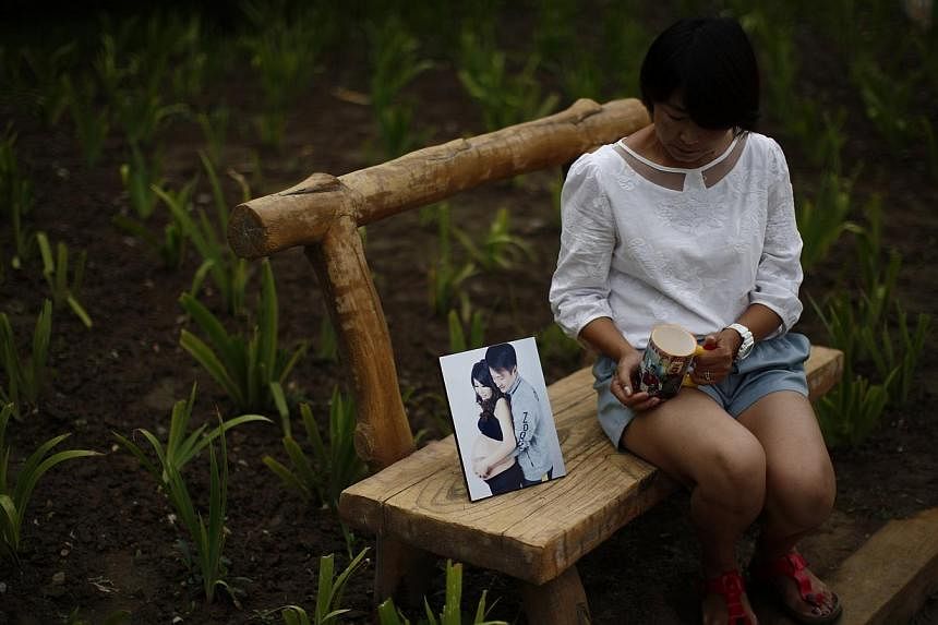 Ms Cheng Liping, whose husband Ju was onboard Malaysia Airlines Flight MH370 which disappeared on March 8, 2014 shows a picture which features she and her husband together, and her husband's cup, at a park near her house where she and her husband use