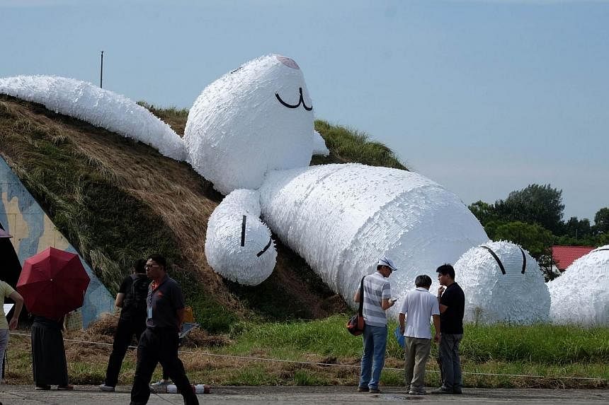 Local residents admire a 25.3m giant rabbit made of plastic and wood and designed by Dutch artist Florentijn Hofman, at an art exhibition in Taoyuan county on Sept 2, 2014. -- PHOTO: AFP