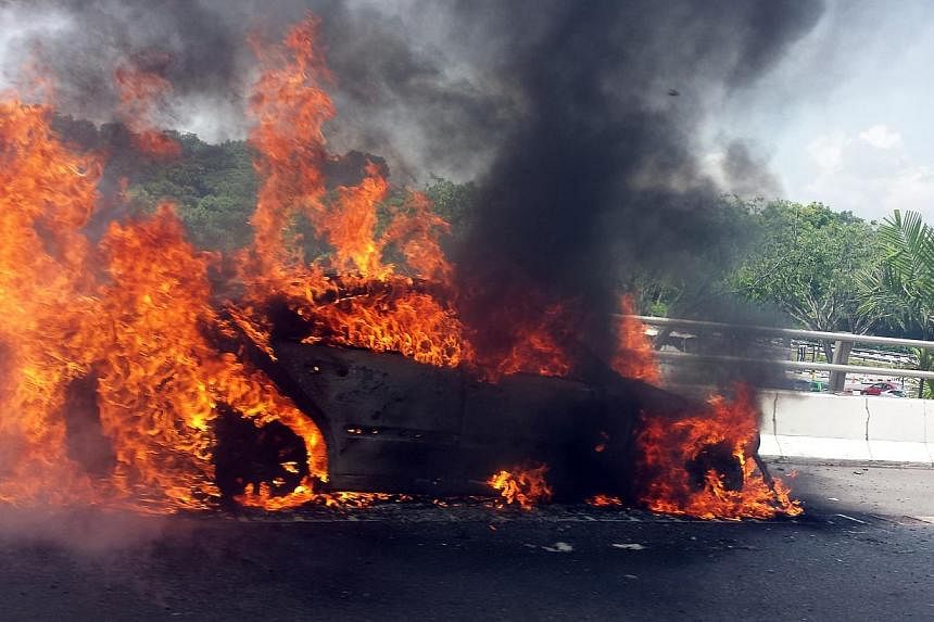 A Mercedes that went up in flames on the Ayer Rajah Expressway near Jurong Pier Road last month. Factors that could lead to car fires include overloading the vehicle with electronic gadgets. -- PHOTO: STOMP
