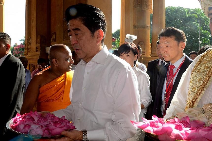 Japanese Prime Minister Shinzo Abe (middle) offered flowers during a visit tp the historic Kelaniya Rajamaha temple in Colombo on Sept 8, 2014, which Buddhists believe was visited by Buddha himself more than 2,500 years ago. -- PHOTO: AFP