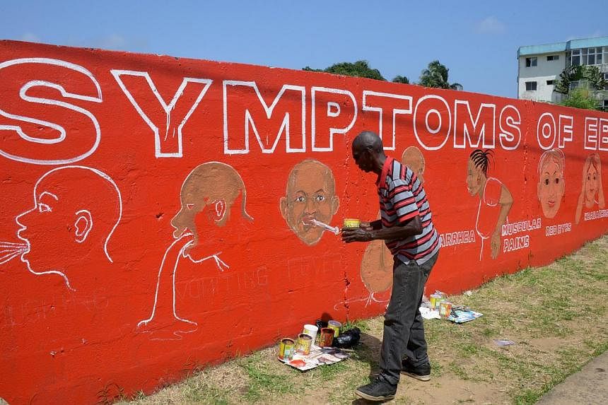 Street artist Stephen Doe painting an educational mural to inform people about the symptoms of the deadly Ebola virus in the Liberian capital Monrovia, on Sept 8, 2014. -- PHOTO: AFP