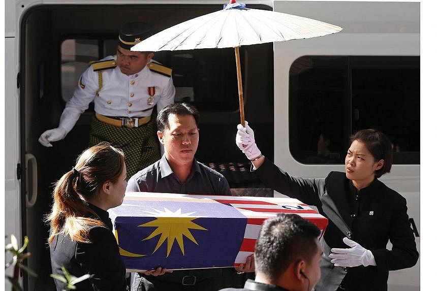 Lt Lee Vee Weng (centre) carries the remains of his one-year-old son Benjamin Lee Jian Han, who was killed in the MH17 crash, into the Xiao En Bereavement Centre in Kuala Lumpur on Sept 9, 2014.&nbsp;-- PHOTO: REUTERS
