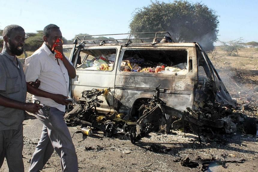 Somali men react as they walk past a burnt out minibus following a suicide attack which targeted a convoy of African Union troops on September 8, 2014. -- PHOTO: AFP