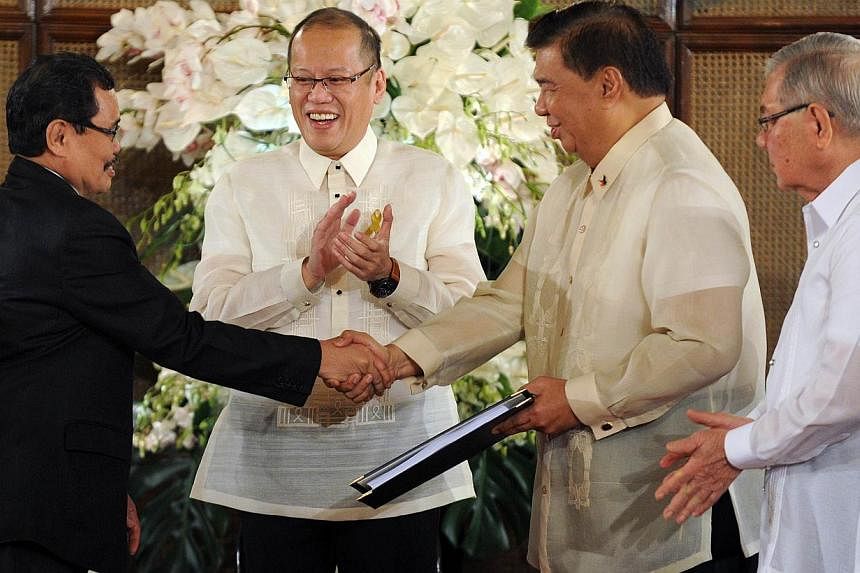 Mohager Iqbal (left), chief peace negotiator of the Moro Islamic Liberation Front (MILF), hands over the draft of the Bangsamoro basic law to Senate President Franklin Drilon (second right) at the Malignancy Palace in Manila on Sept 10, 2014 as Phili
