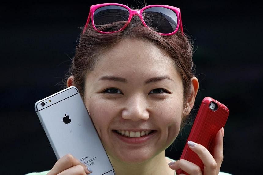 A woman holds a mock iPhone 6 plus (left) and an iPhone 5s as she waits in a line, ahead of the Sept 19 release of iPhone 6 and iPhone 6 Plus, in front of an Apple Store at Tokyo's Ginza shopping district ib Sept 10, 2014. -- PHOTO: REUTERS