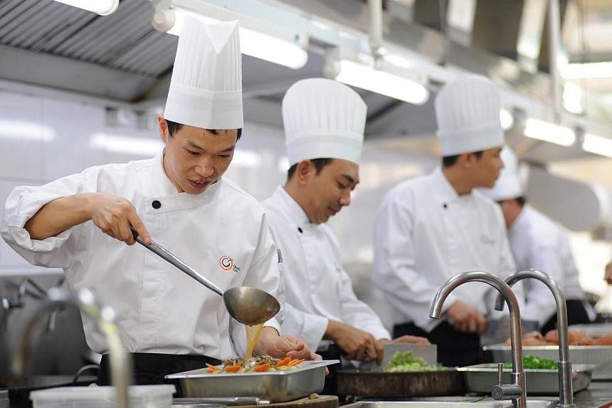 Chefs working in a kitchen, one of the four central kitchens by food caterer Neo Group. -- PHOTO: NEO GROUP