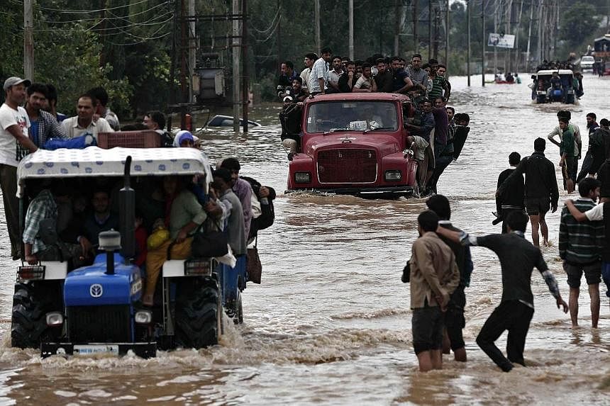 Vehicles evacuating Kashmiri flood victims to higher grounds travel through a flooded street in Srinagar on Sept 9, 2014.&nbsp;Flood waters started receding in Indian Kashmir on Wednesday, Sept 10, giving rescue teams a chance to reach tens of thousa
