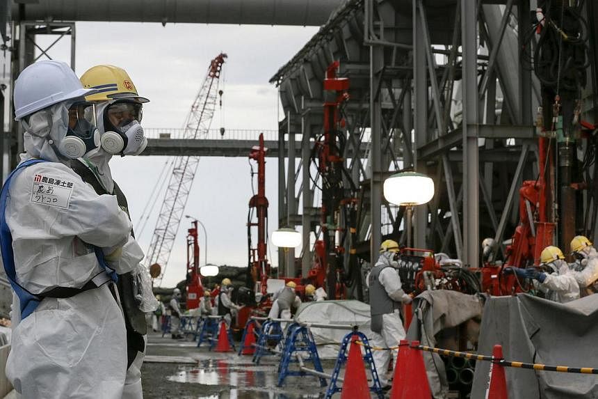 Workers conduct operations to construct an underground ice wall at Tokyo Electric Power Co.'s (Tepco) tsunami-crippled Fukushima Daiichi nuclear power plant in Fukushima Prefecture on July 9, 2014. -- PHOTO: REUTERS