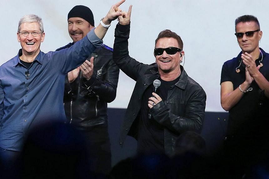 Apple CEO Tim Cook (left) greets the crowd with U2 members (from right) Larry Mullen Jr, Bono and The Edge during an Apple special event at the Flint Center for the Performing Arts on Sept 9, 2014, in Cupertino, California. -- PHOTO: AFP