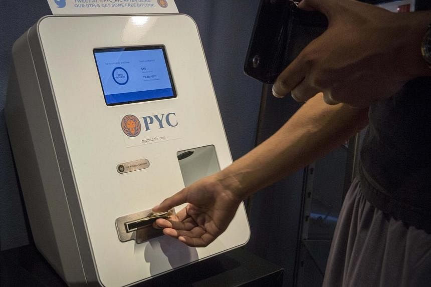 A customer feeds cash currency in to a Bitcoin ATM located in Flat 128, a boutique in New York's West Village on Aug 22, 2014. -- PHOTO: REUTERS