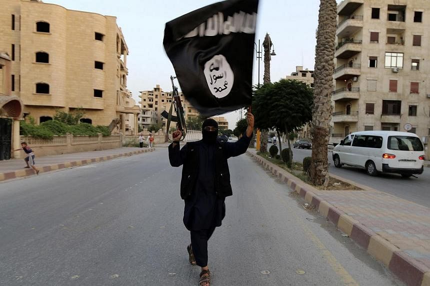 A member loyal to the Islamic State in Iraq and the Levant (ISIL) waves an ISIL flag in Raqqa, Syria in this file photograph. According to reports from Malaysia, a Penang-born man has taken his Singaporean wife and two children to Syria to join the j