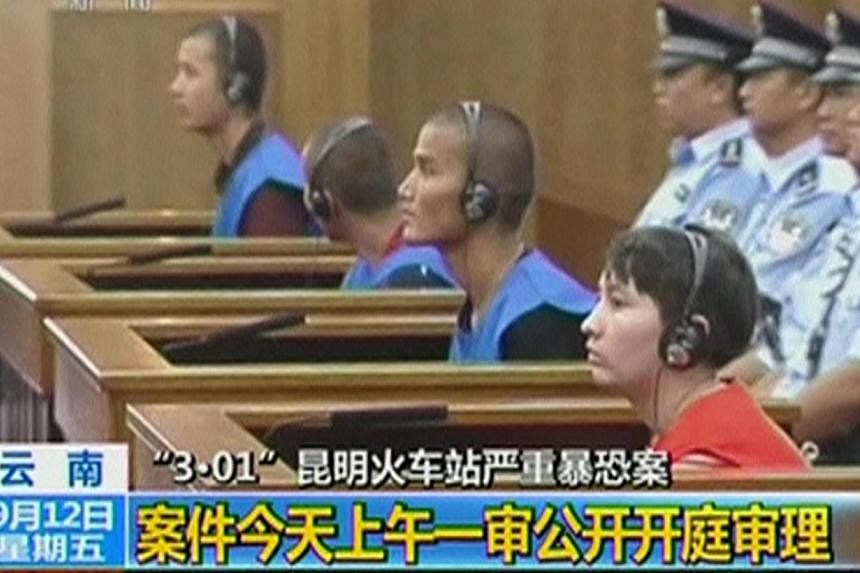 Defendants sit in front of police officers at a courtroom in Kunming City during the trial of four people accused of participating in an attack at a train station in southwestern China, in this still image taken from video on Sept 12, 2014.&nbsp;Thre