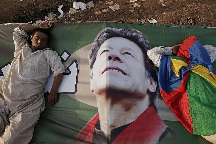 Supporters of Imran Khan, the chairman of the Pakistan Tehreek-e-Insaf (PTI) political party, taking a nap on his campaign banner during what has been dubbed a "freedom march" in Islamabad on August 25, 2014. Mr Khan and cleric Tahir ul-Qadri, who co