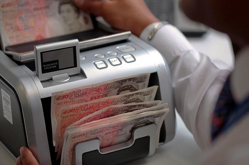 An employee feeds fifty pound notes through an automated currency counting machine at a Travelex store in London, UK.&nbsp;The pound and the euro have been falling, and it's come as good news to Singaporeans. --PHOTO: BLOOMBERG