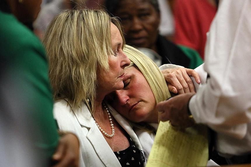 June Steenkamp (left), mother of Reeva Steenkamp, holds her cousin Kim Martin as judgment is handed down in the murder trial of South African Paralympic athlete Oscar Pistorius in the High Court in Pretoria on Sept 12, 2014, where Pistorius was found