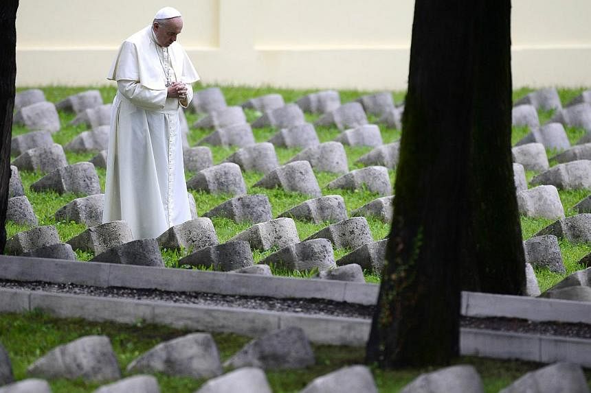 Pope Francis prays as he stands among graves at the military cemetary of the World War I memorial of Redipuglia, near Gorizia, northern Italy on Sept 13, 2014. -- PHOTO: AFP