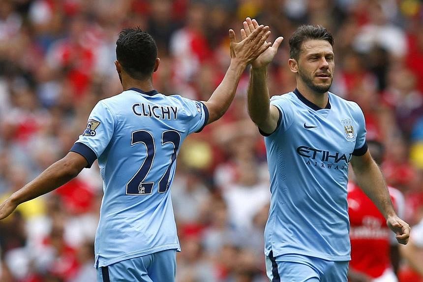 Manchester City's Martin Demichelis (right) celebrates with teammate Gael Clichy after scoring against Arsenal during their English Premier League match at the Emirates stadium in London on Sept 13, 2014. -- PHOTO: REUTERS