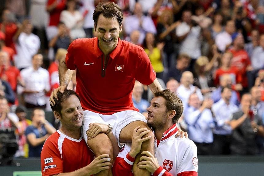 Switzerland's captain Severin Luethi (left) and Switzerland's Stan Wawrinka (right) carry their teammate Roger Federer as they celebrate winning the Davis Cup semi-final against Italy on Sept 14, 2014 in Geneva. -- PHOTO: AFP