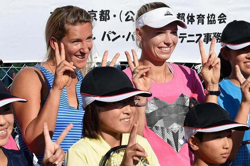Caroline Wozniacki (top centre) of Denmark and Victoria Azarenka (top left) of Berarus pose for photographers during a charity tennis school event for children invited from the March 11, 2011 earthquake and tsunami-hit areas, at the Pan Pacific Open 
