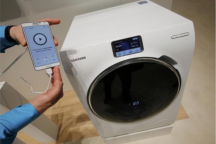 A Samsung employee holds a smartphone remotely controlling a WW9000 washing machine at the IFA consumer technology fair in Berlin, on Sept 5, 2014.&nbsp;Samsung has accused the head of rival LG Electronics's home appliances business of damaging Samsu