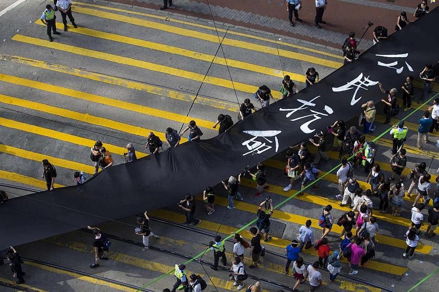 Occupy Central protesters march with a 500m long black cloth, which they say symbolises the loss of credibility in Beijing's refusal to allow true democracy in Hong Kong, on Sept 14, 2014.&nbsp;-- PHOTO: REUTERS