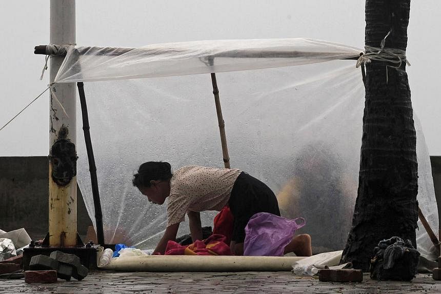 A woman shields herself with a plastic sheet from the rain brought on by Typhoon Kalmaegi, also called Luis, on the street at a bay in Manila on Sunday, Sept 14, 2014.&nbsp;The typhoon slammed into the rice-producing Philippine northern region on Sun