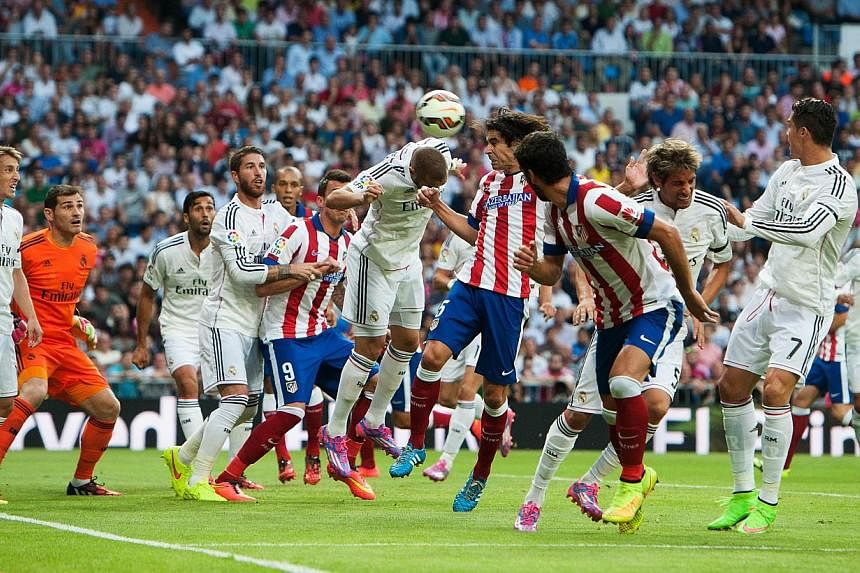 Atletico Madrid's Portuguese midfielder Tiago Mendes (centre) heads the ball to score during the Spanish league football match against Real Madrid CF at the Santiago Bernabeu stadium in Madrid on Sept 13, 2014. -- PHOTO: AFP