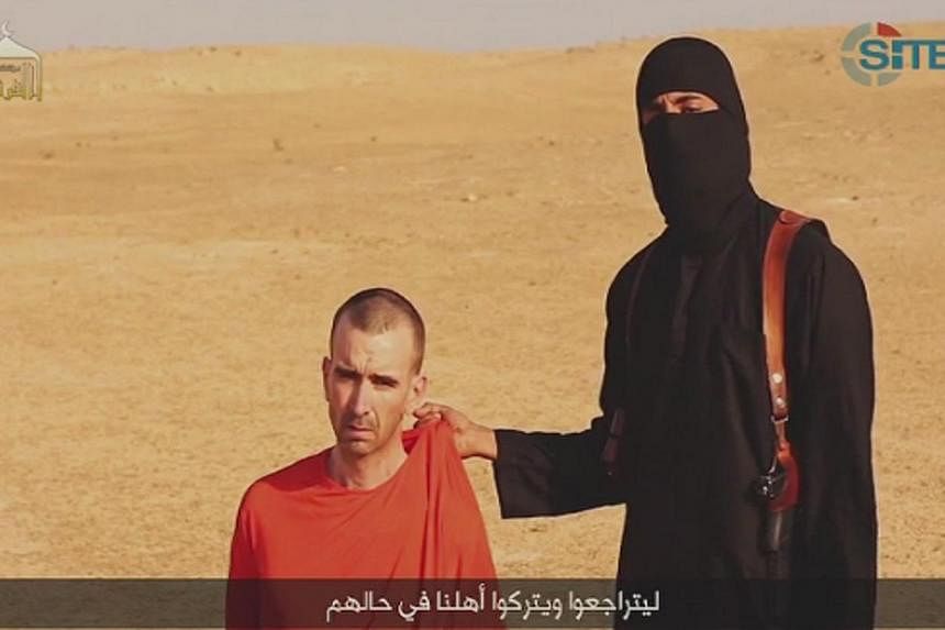 A video purportedly showing threats being made to a man Islamic State (IS) named as David Haines by a masked IS fighter in an unknown location in this still image from video released by Islamic State on Sept 2, 2014. -- PHOTO: REUTERS