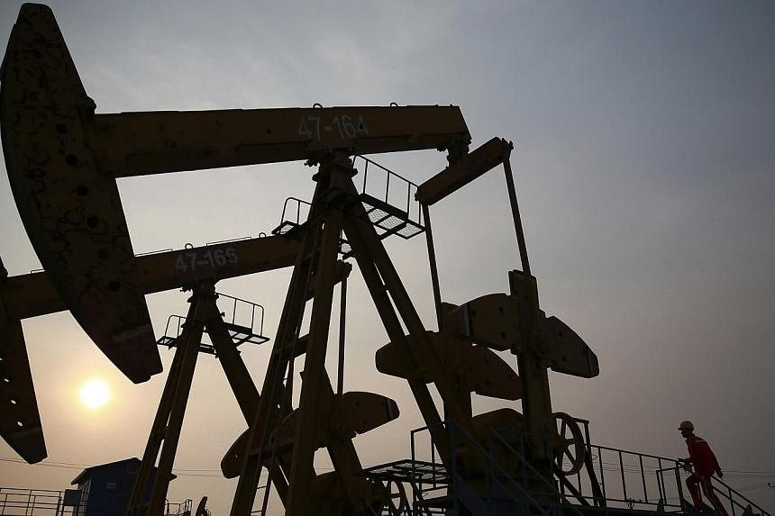 A worker examines a pumpjack at a PetroChina oil field in Panjin, Liaoning province, in this June 30, 2014 file photo.&nbsp;China's central state-owned enterprises (SOEs) are expected to invest one trillion yuan (S$205.9 billion) in the rustbelt nort