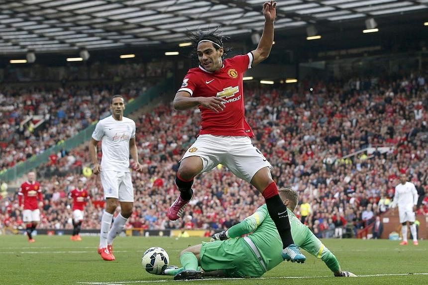Manchester United's Radamel Falcao (front) is challenged by Queens Park Rangers' goalkeeper Robert Green (right) during their English Premier League football match at Old Trafford in Manchester, northern England on Sept 14, 2014. -- PHOTO: REUTERS