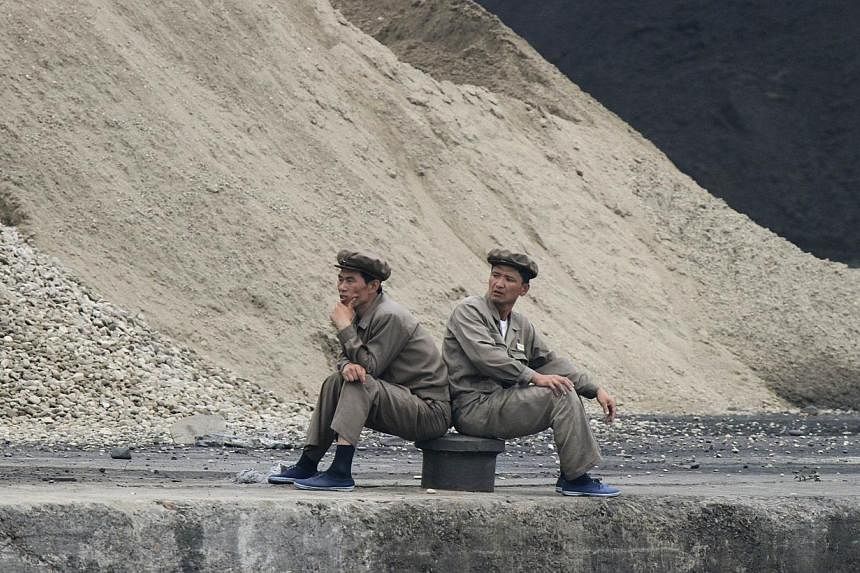 North Koreans sit along the banks of the Yalu River near the North Korean town of Sinuiju, opposite the Chinese border city of Dandong on June 25, 2014.&nbsp;A South Korean man who tried to defect to North Korea by crossing into it through the river 