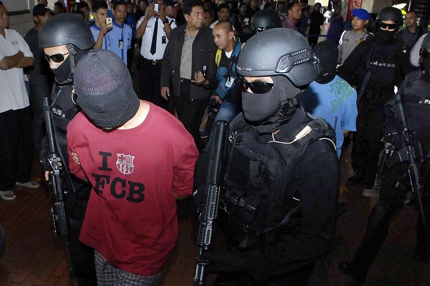 Indonesian anti-terror policemen escorting the men arrested through Jakarta airport on Sept 14, 2014. The Indonesian authorities say the suspected terrorists were trying to meet wanted militant leader Santoso, who swore allegiance to ISIS leader Abu 