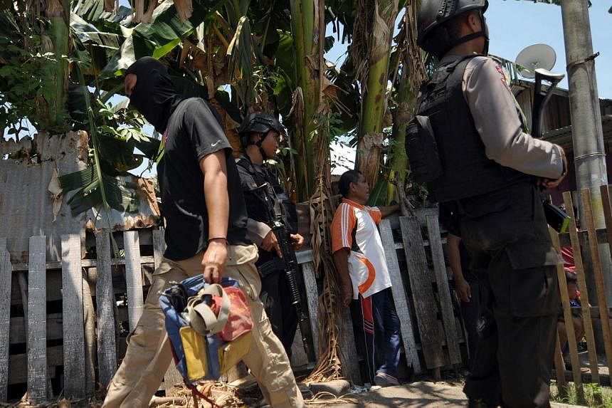 Indonesian anti-terror police Densus 88 (left) carries evidence from a house rented by terror suspects arrested in an earlier raid, in Palu on Sept 16, 2014.&nbsp;Indonesia's anti-terrorism police, who have arrested four Chinese Uighur jihadists link