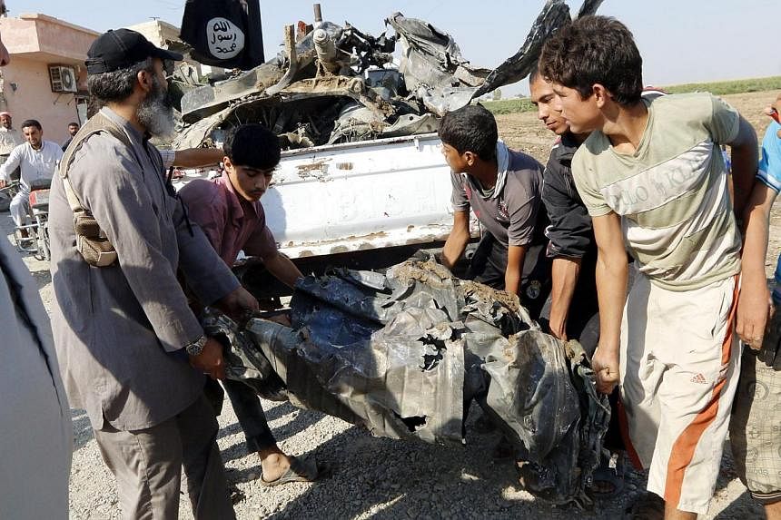 People carry a remnant of a war plane that crashed on the outskirts of Raqqa in northeast Syria on Sept 16, 2014.&nbsp;Jihadists shot down a Syrian warplane conducting strikes on the Islamic State of Iraq and Syria (ISIS) group stronghold of Raqa on 