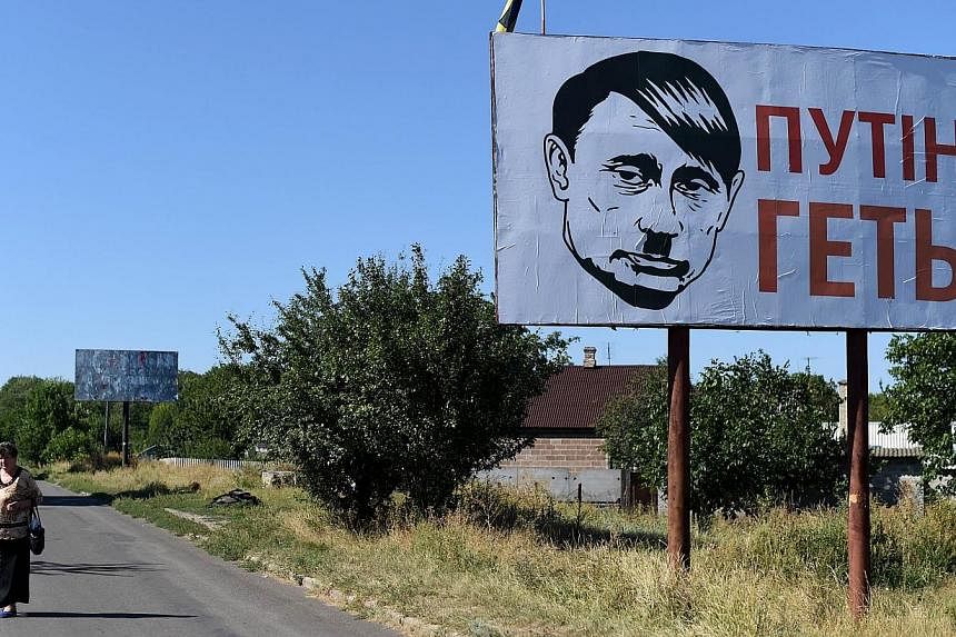 A villager walks past an Ukrainian billboard despicting Russian president Vladimir Putin bearing a Hitler moustache and haircut in Volnovakha near Donetsk, on Aug 26, 2014. Russia said on Monday that it would probe Euronews after the news channel bro