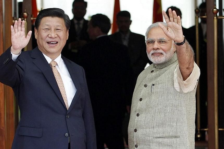 India's Prime Minister Narendra Modi (right) and China's President Xi Jinping wave before their meeting in the western Indian city of Ahmedabad on Sept 17, 2014.&nbsp;India's new prime minister rolled out the red carpet for Chinese President Xi Jinpi