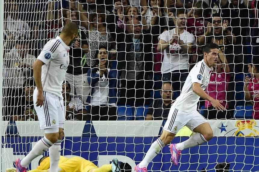 Real Madrid's Colombian midfielder James Rodriguez (right) celebrates after scoring during the Uefa Champions League football match Real Madrid CF vs FC Basel 1893 at the Santiago Bernabeu stadium in Madrid on Sept 16, 2014. -- PHOTO: AFP